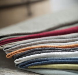 A pile of folded cotton fabric of various colors placed on a wooden surface